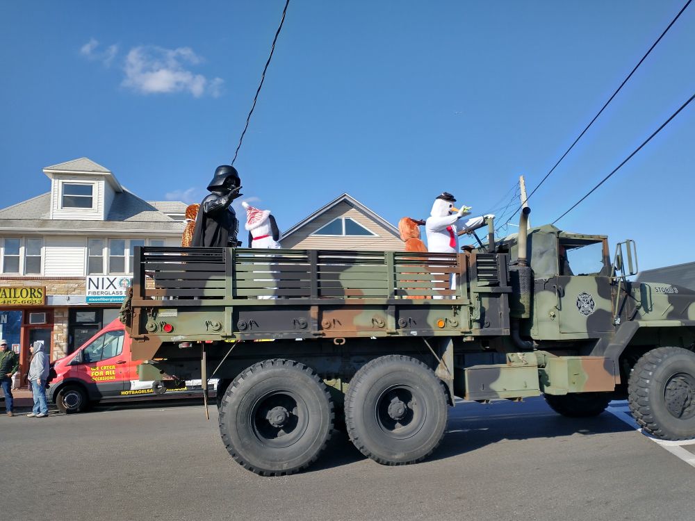 Christmas parade with Darth Vader, Frosty the Snowman, and other characters on the back of a military truck