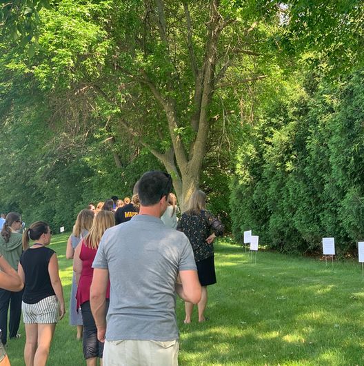 An image from the linked article, showing several staff members walking through a grassy area, looking at a row of white signs.