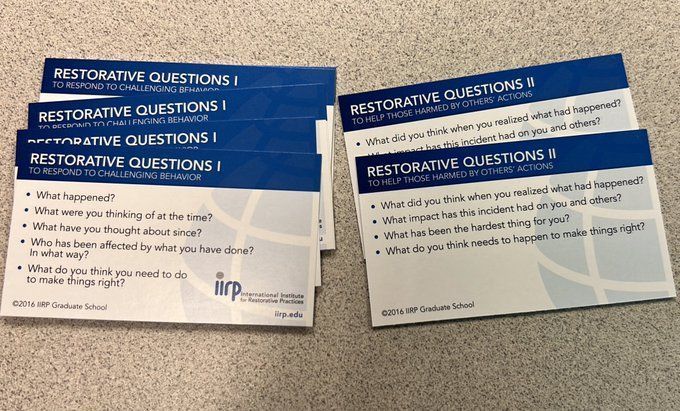 Two stacks of cards with restorative questions for responding to challenging behavior, such as "What have you thought about at the time? What have you thought about since? What do you think you need to do to make it right?"
