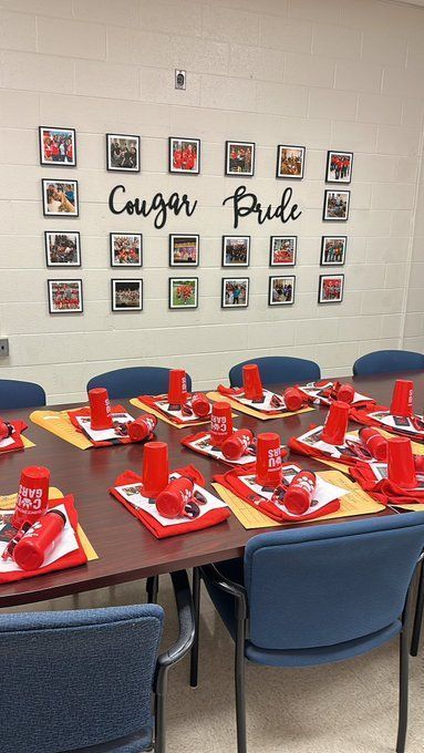 Conference room table with the words "Cougar Pride" visible on a wall in the background. On the table are several small piles of school "swag" for new staff.