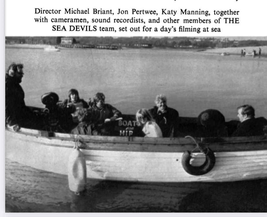 Behind-the-scenes photo of the production crew and key actors aboard a boat during the making of the 1972 Doctor Who story ‘The Sea Devils’. Features actors Jon Pertwee and Katy Manning, along with members of the filming crew including director Michael E. Briant.