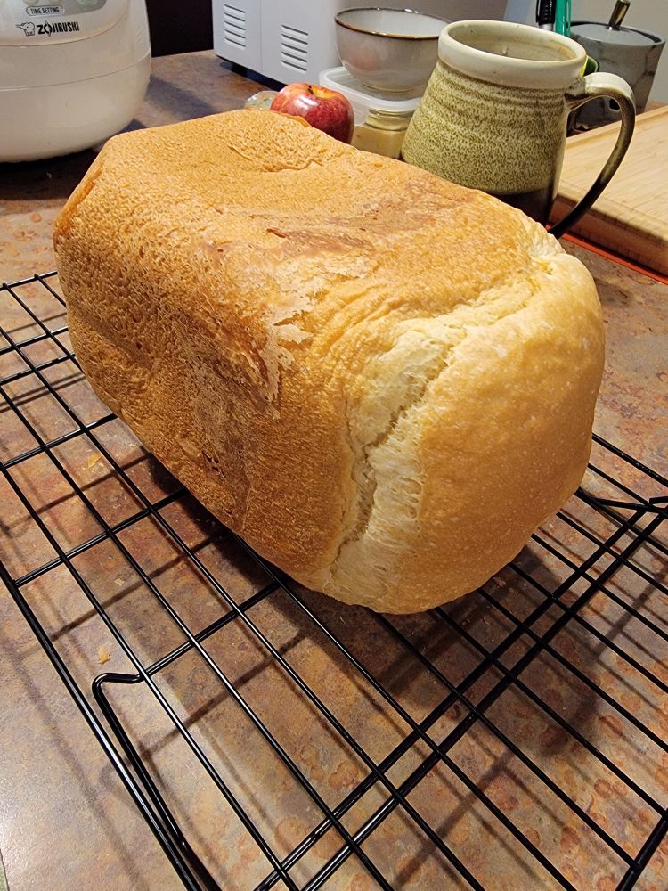A very square loaf of bread on a cooling rack.
