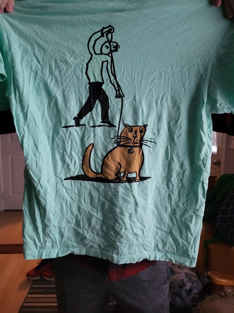 A shirt. On the shirt is a poorly drawn man, walking a poorly drawn cat.