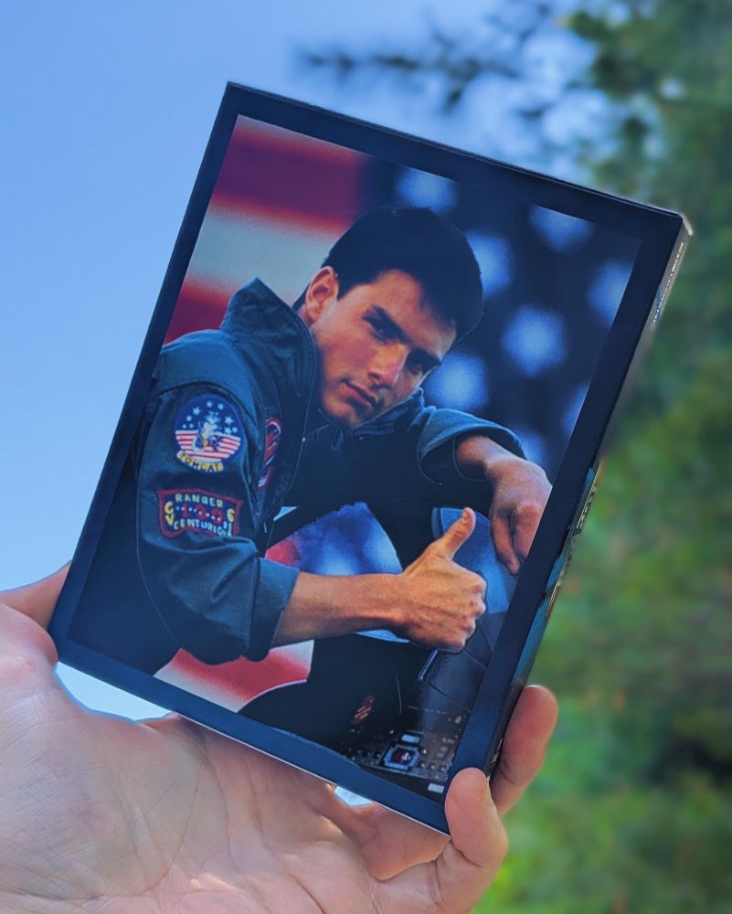 Back of MantaLab slipcase for Top gun. Tom Cruise in a pilots jumpsuit giving the thumbs up to camera with a big American flag behind him.