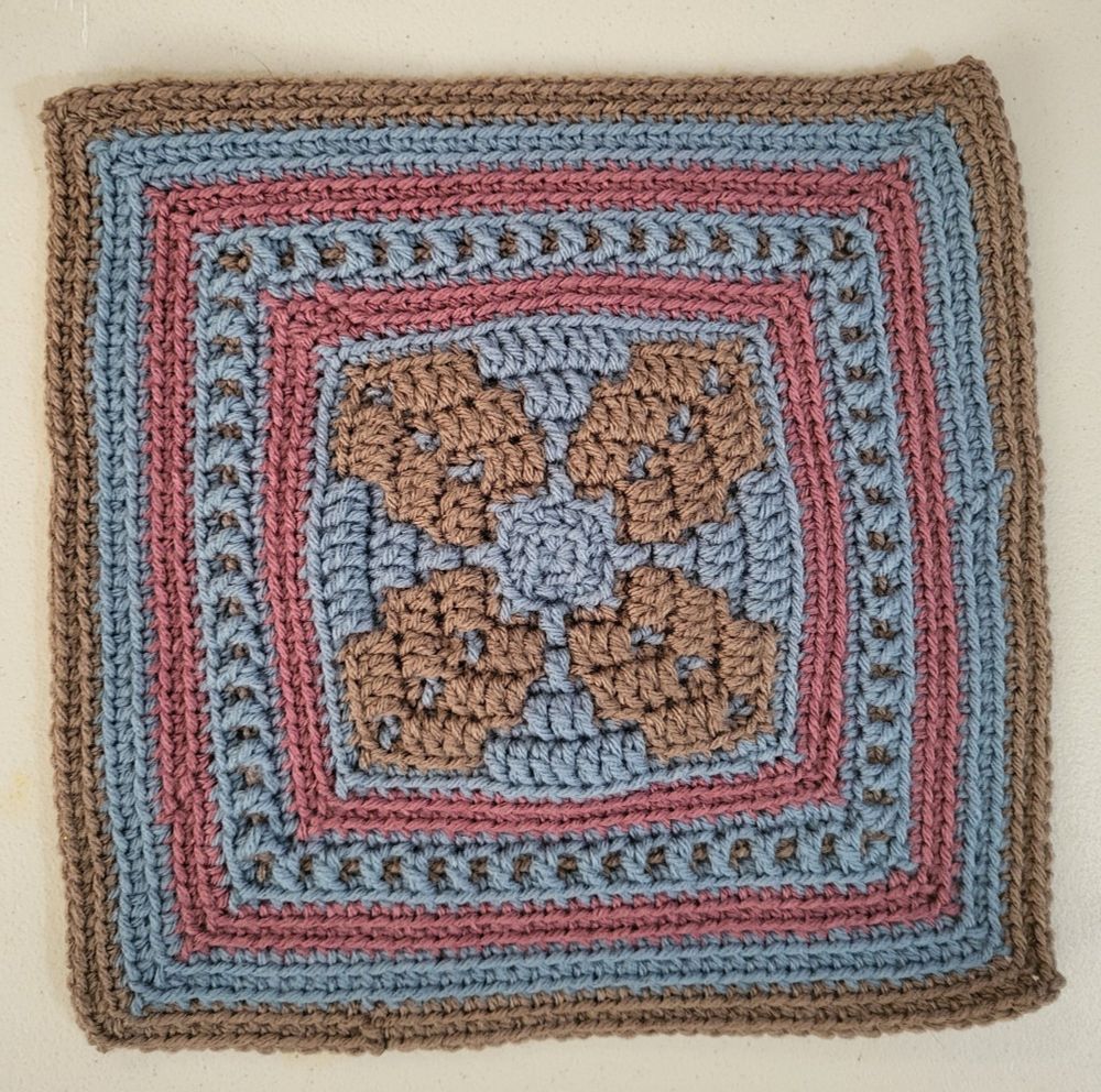 Crochet block done in brown, blue and pink.