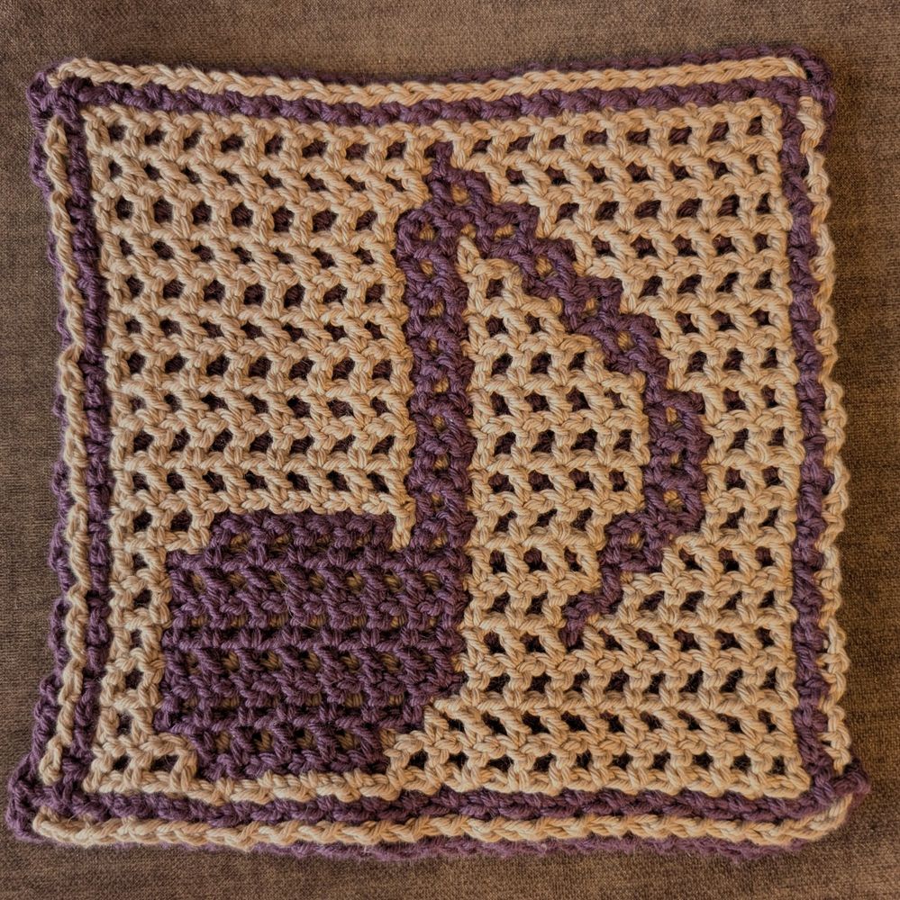 A washcloth done in interlock filet crochet. It is a dark purple music note on a light gray background. End of description.