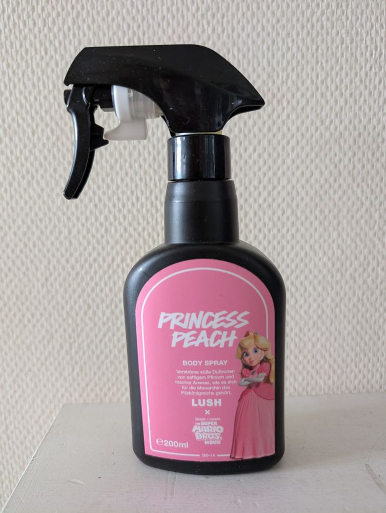 Princess Peach body spray. Svart sprayflaske med rosa etikett med motiv av Princess Peach og tekst. 