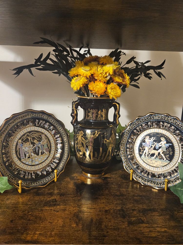 I am so sorry, I'm not sure how to describe these 😭. They're apart of a tea time display set from like the 1970s up to the 1990s handmade in Greece. They are on my walnut brown booklself. They have an ancient Greek style of drawing (two plates and a vase). They're all black with gold Greek style drawings on them but the plates have a bit of colour in the middle. The Vase in the middle has dried golden yellow follows in them along with some Eucalyptus leaves.