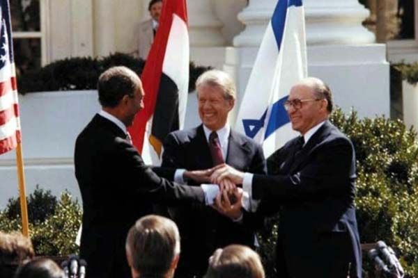 President Jimmy Carter, Egyptian President Anwar Sadat, and Israeli Prime Minister Menachem Begin join hands on the White House lawn following the ceremonial signing of the Camp David Accords.