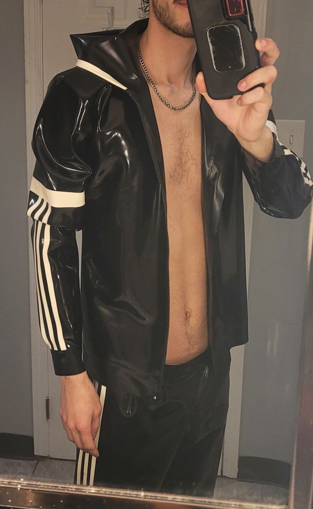 Boy in rubber/latex tracksuit in front of mirror
