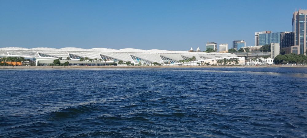 museu do amanhã no Rio de Janeiro visto ao longe de um barco. É possível ver as águas da Bahia de Guanabara e o prédio do museu de lado
