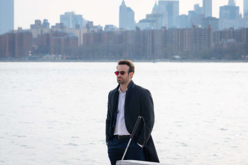 Charlie Cox as Matt Murdock, standing by the river, Manhattan in the background