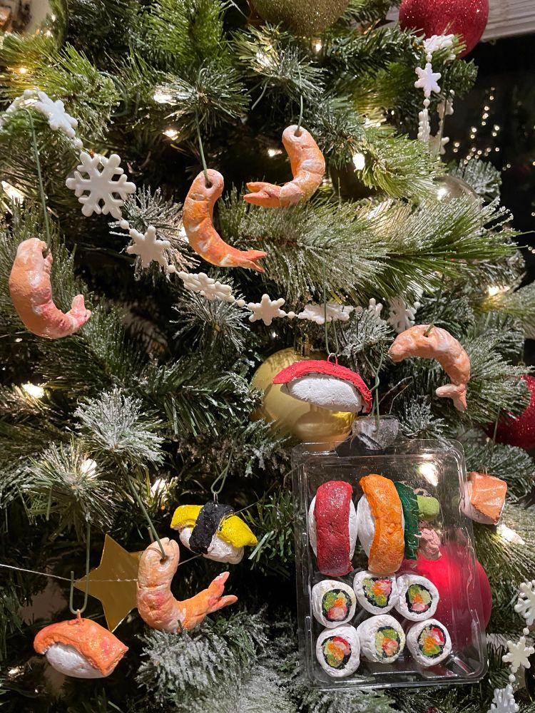 Hand sculpted and hand painted ornaments, made to look like many individual cooked/peeled shrimps, various individual nigiri, and a little clear plastic tray with California rolls, nigiri, wasabi and ginger. All hanging on a Christmas tree with disgusting white flocking on the branches and other store bought ornaments and lights.