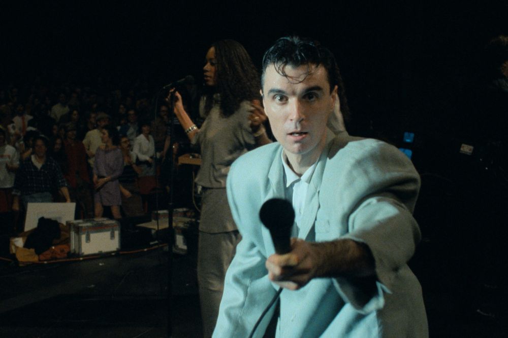 David Byrne holding a microphone at the camera during Stop Making Sense
