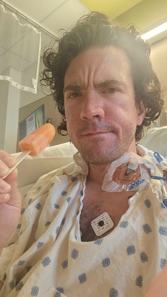 selfie of me eating a popsicle in my hospital bed, feeling increasingly unhappy with my bilirubin level