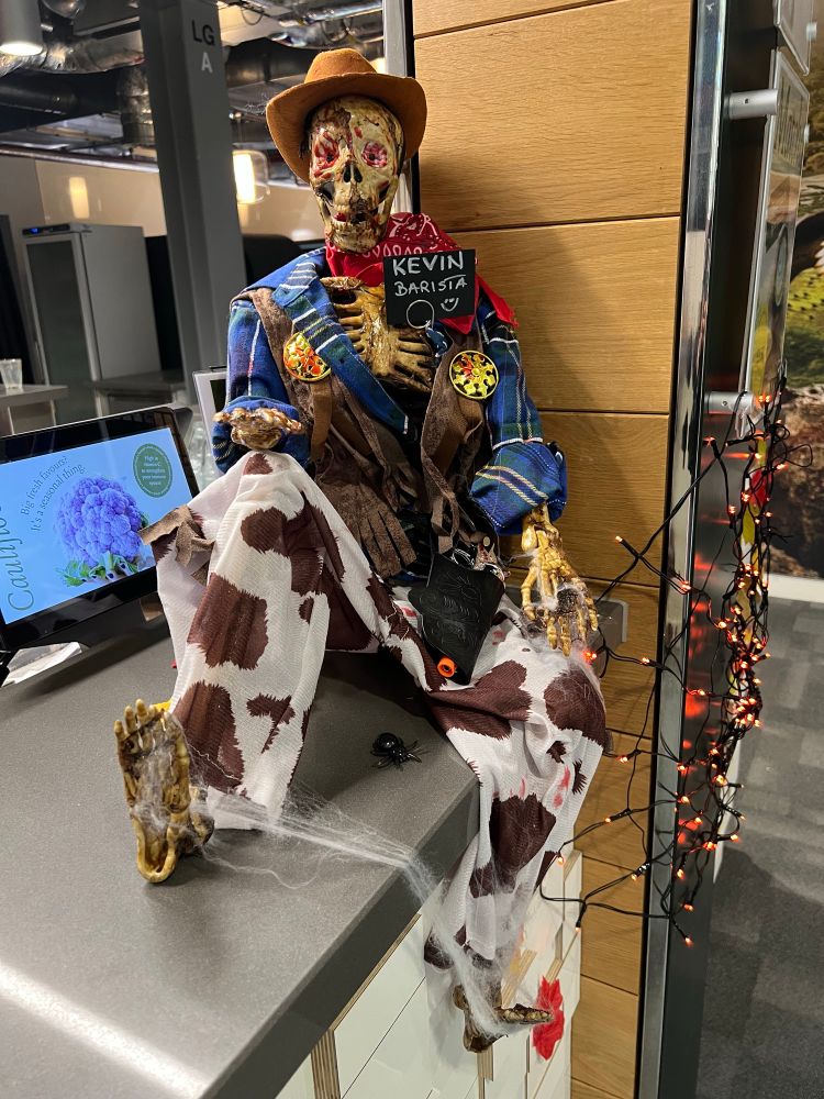 Skeleton dressed as a cowboy skirting on the coffee bar counter top. He wears a badge reading “Kevin Barista”.