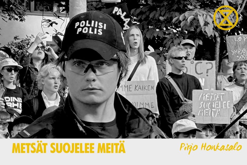 Valokuva, jossa vakava poliisi katsoo kameraa kohti. Taustalla mielenosoittajia.
