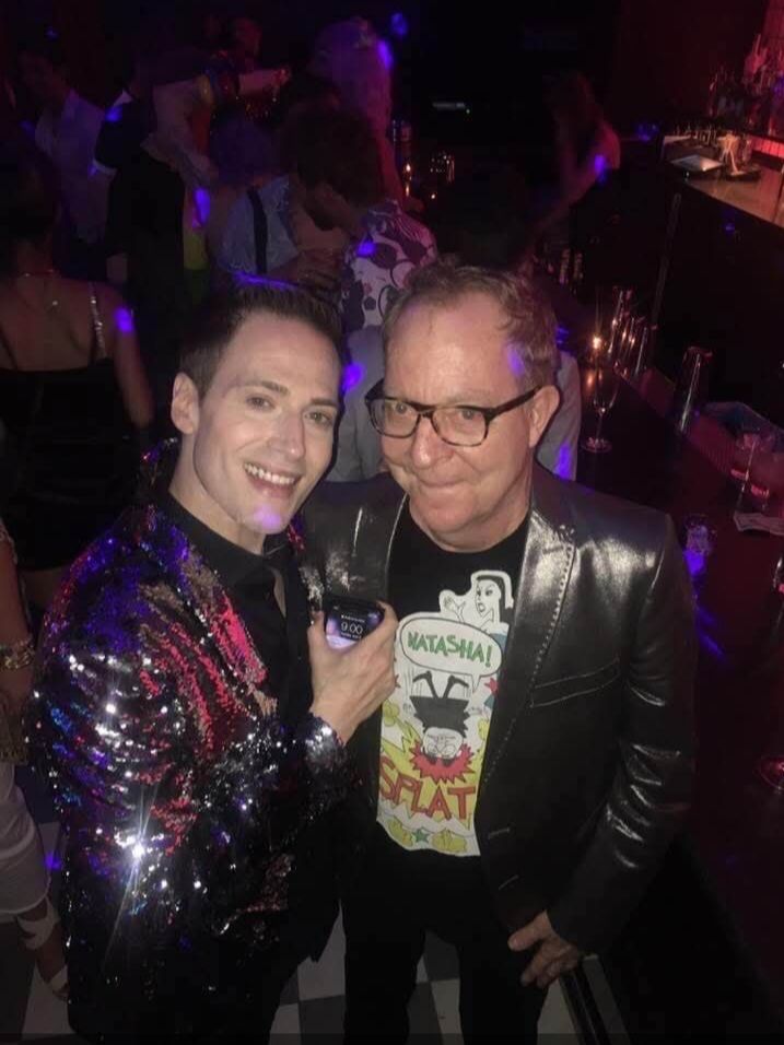 Randy Rainbow with Fred Schneider at a bar and both have shiny jackets on. 