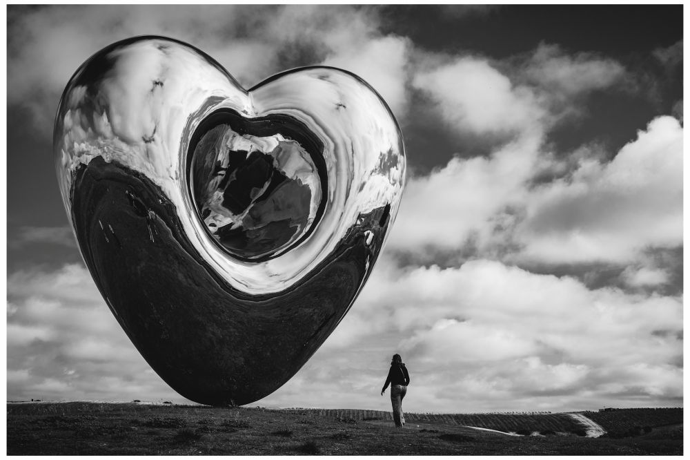 A woman walks toward a giant metallic heart perched on a hilltop. The sculpture’s rounded silhouette and central indentation warp the reflection of the landscape and cloud filled sky. 

Sculpture: Richard Hudson’s “Love Me”, 2016
Taken at Donum Estates, Sonoma, CA

This is a different view of the sculpture in my earlier post showing a side view of the “pregnant belly” and the reflection in full color. 