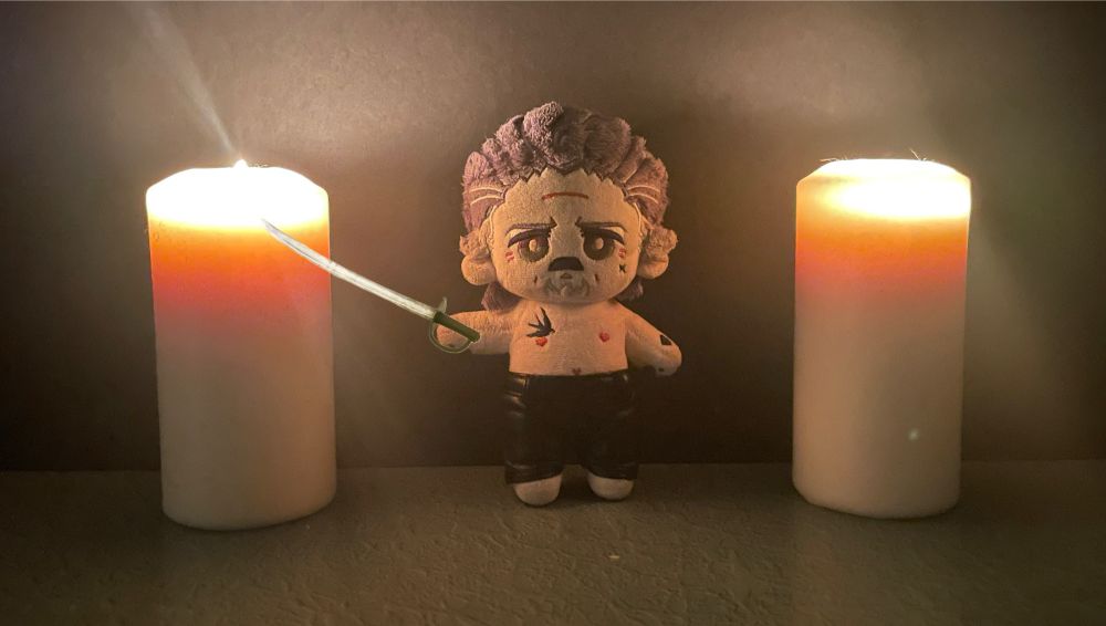 Izzy doll by Rights, wearing only a pair of black leather pants, holding a sword, while flanked by two candles.