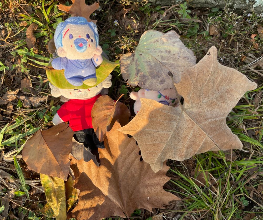 15 CM Izzy, snake egg Izzy, and tits Izzy, all by rights, playing in a small pile of leaves in different shades of brown and green.
