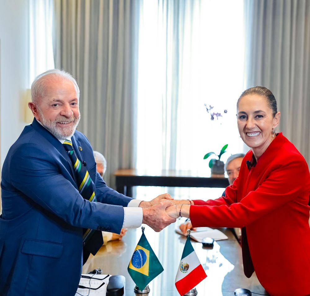 Presidente Lula e a presidenta do México, Claudia Sheinbaum, trocam aperto de mão olhando para a câmera 