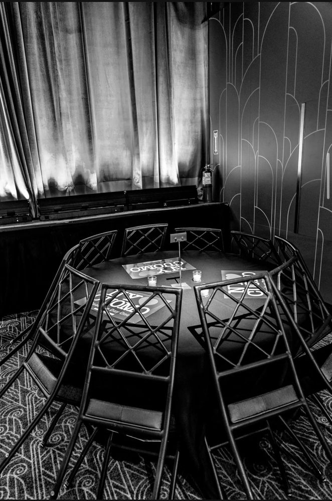 A photo of chairs leaning against a round table after closing, with multiple Cuomo loves New York signs sitting abandoned. 