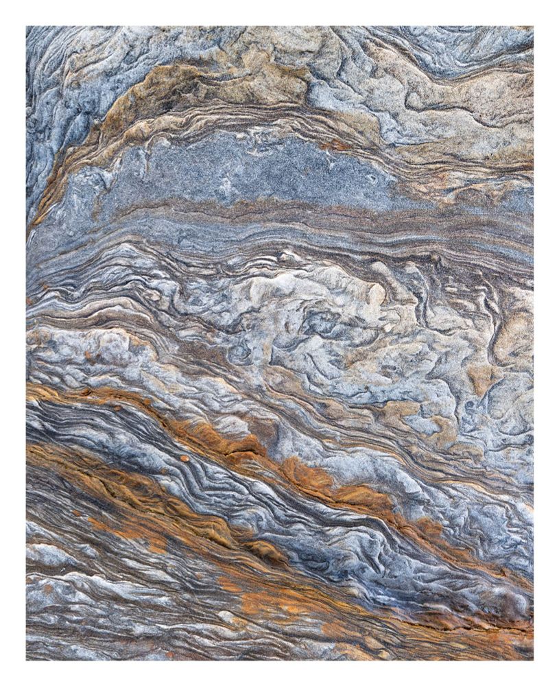 Swirling layers of grey, beige, steel blue and rusty orange.  This is actually a close up image of some rocks, but it resembles the patterns and colours you see in the outer atmosphere of the planet Jupiter.