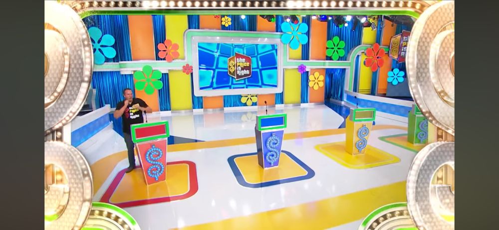 The opening to a Season 49 episode of The Price Is Right, with socially distanced One Bid podiums and the audience section “paved over” with empty floor
