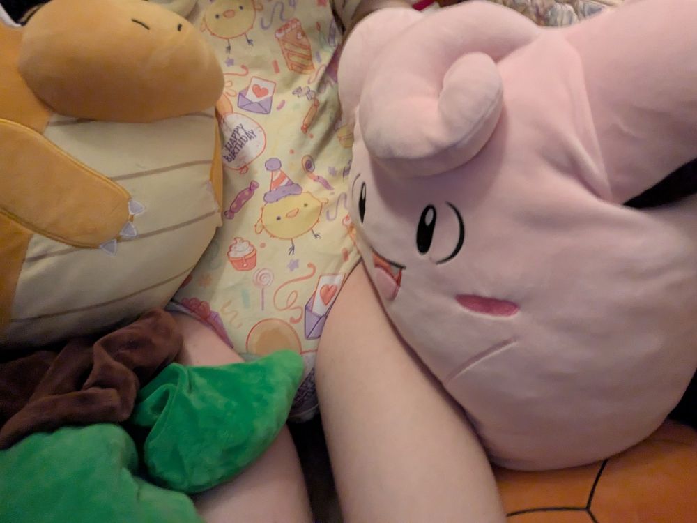 Dee in plushie pile wearing onesie