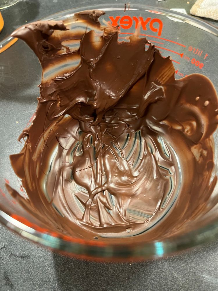 A closeup of a mess of hardened melted chocolate inside a glass Pyrex measuring bowl
