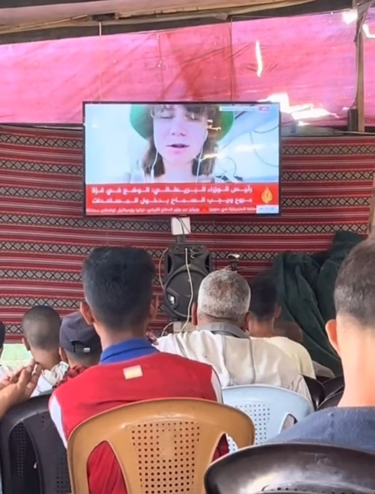 Some Gazans are watching TV under a tent, where Greta Thunberg is speaking.

