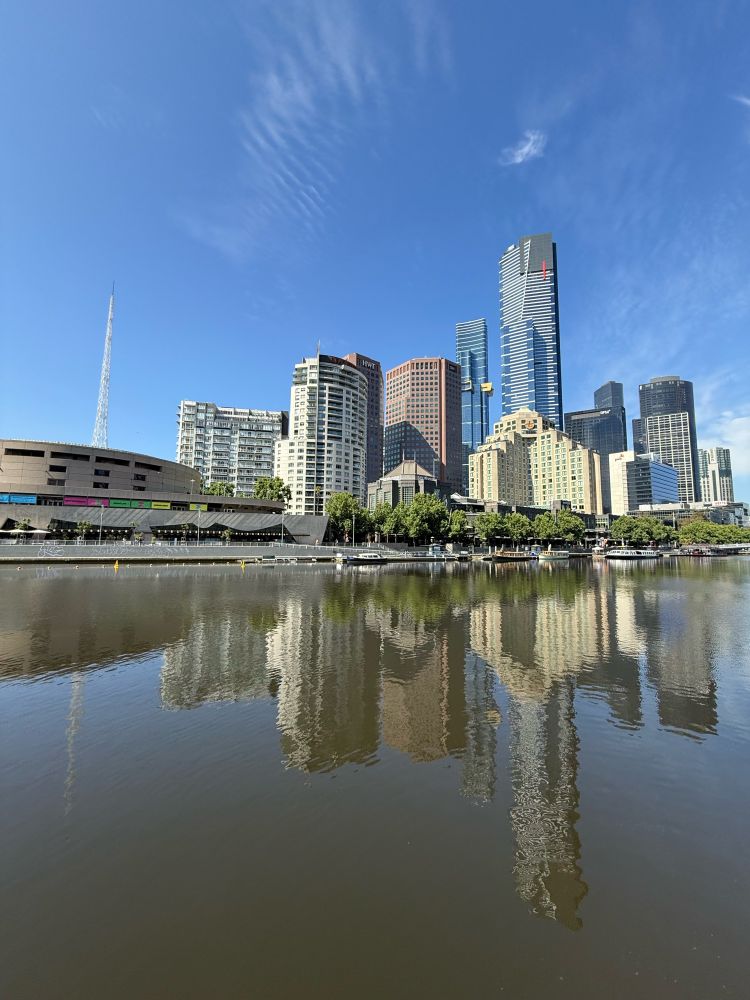 A photo of buildings in Southbank in Melbourne/Naarm across the Yarra River. The sky is blue.