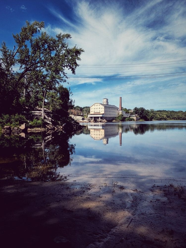 View of a lazy bend of the Androscoggin River with a classic Maine bright blue summer sky complete with feathery white clouds