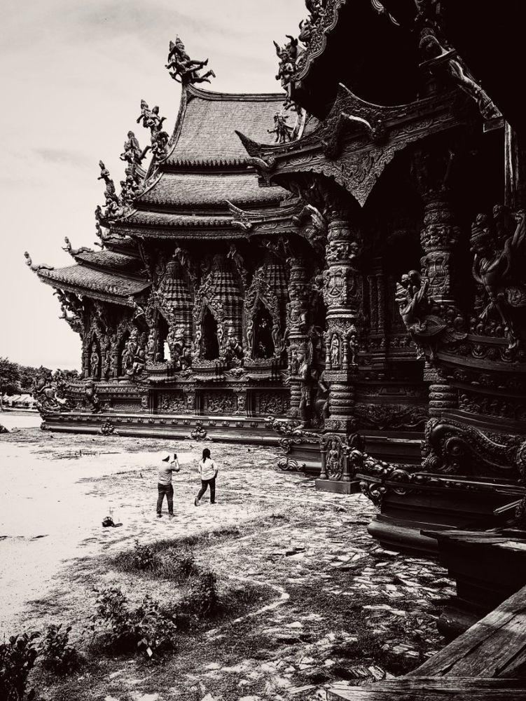 Two tourists taking selfies are dwarfed by the sheer size and length of the ornately carved Sanctuary of Truth, it's impressive wooden structure handmade and hewn together with our any nails or metal supports