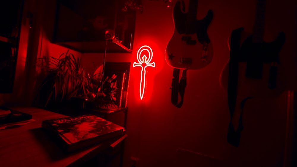 Room with guitars on wall lit up by a red vampire ankh neon