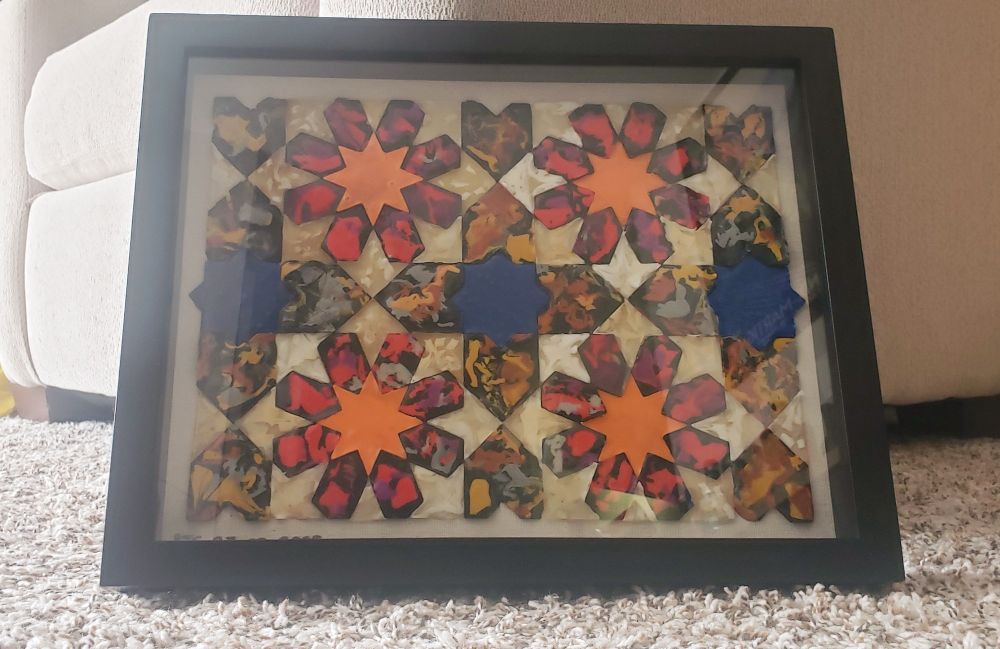 The finished panel of recycled plastic tiles, framed in a shadow box
