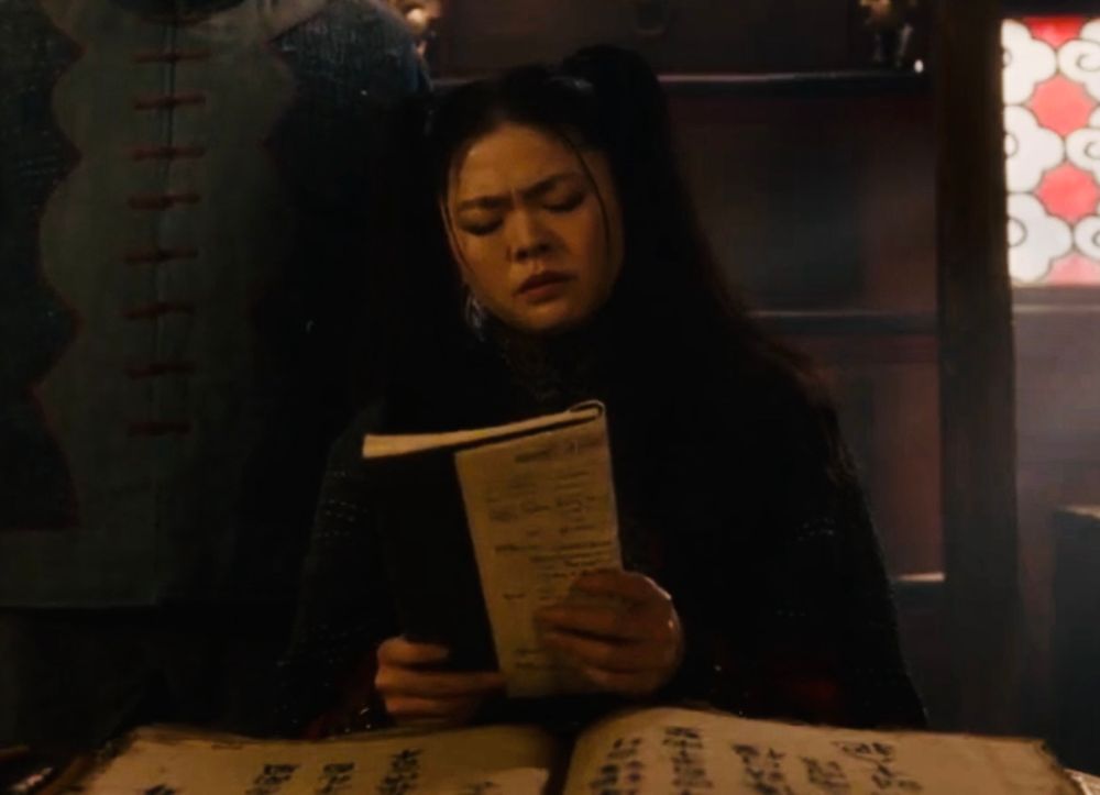 Image from OFMD S2 E3. Zheng Yi Sao reads a book Auntie hands to her as the two discuss the damaged Revenge ship.