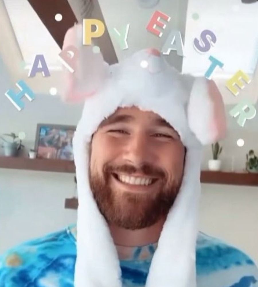 Travis kelce wearing bunny ears with Happy Easter written on the screen