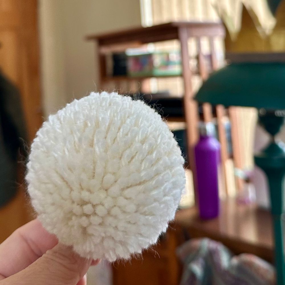 Closeup pic of a round, white, wool pom-pom