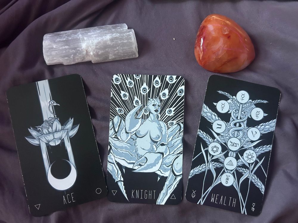 Tarot spread with a selenite crystal and carnelian crystal above it.