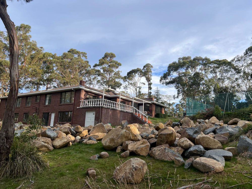 A large suburban house with its backyard covered in boulders