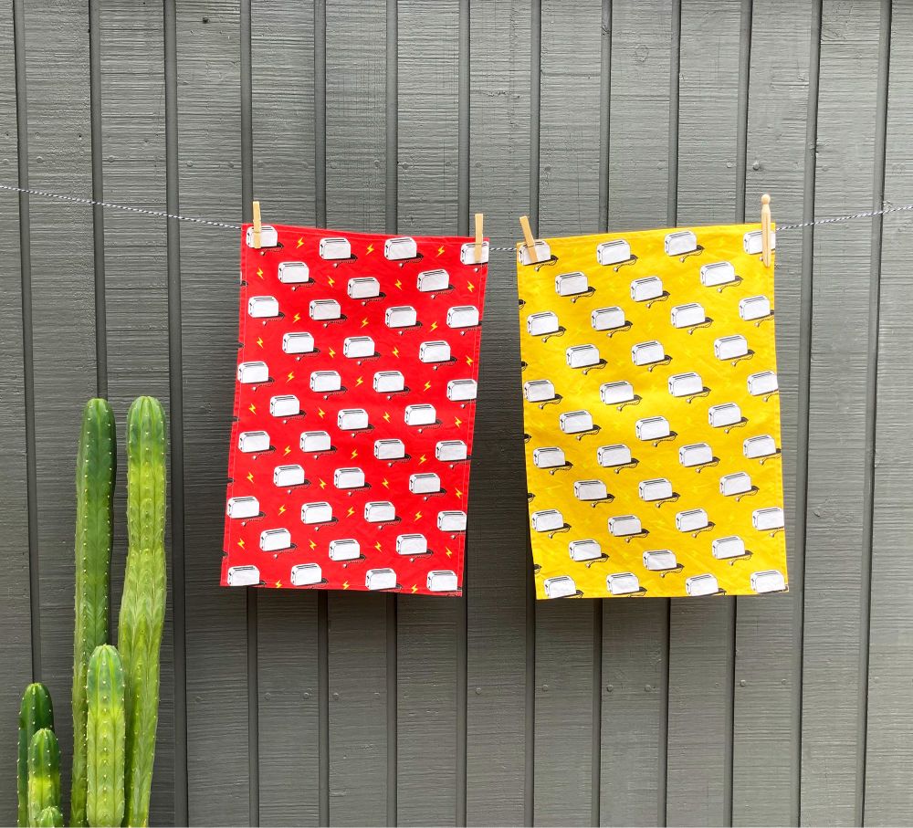 Two tea towels hanging on a line next to a cactus