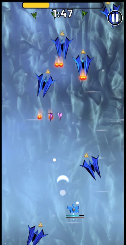 Vertical-oriented screenshot of your blue gunship near the bottom, shooting crescent-shaped and circle-shaped bullets, at its enemies. 

There are small purple and green ships that are AI-powered, as well as larger, blue ships that shoot red fireball bullets. 

The epic rights take place over the snow-covered Andes mountains.