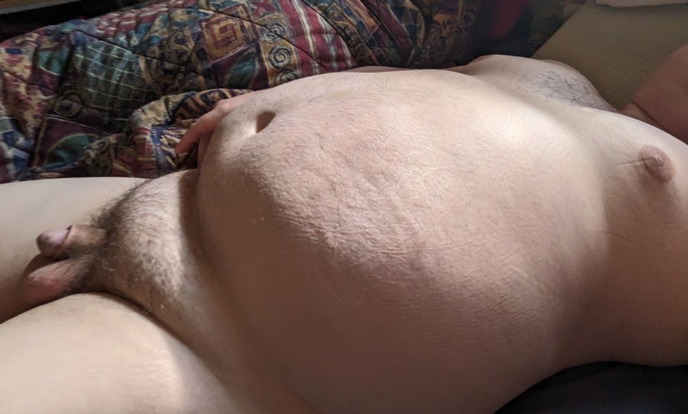 Photo of a nude obese Caucasian male laying on a bed