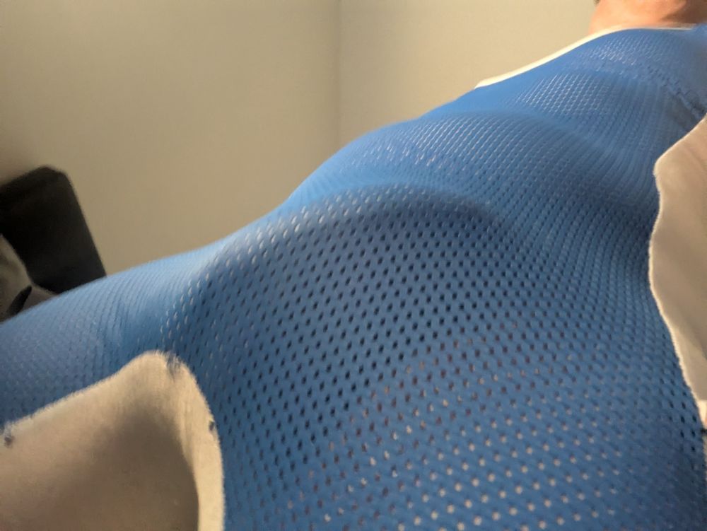 Erect penis beneath strained blue mesh fabric, a wrestling singlet. 