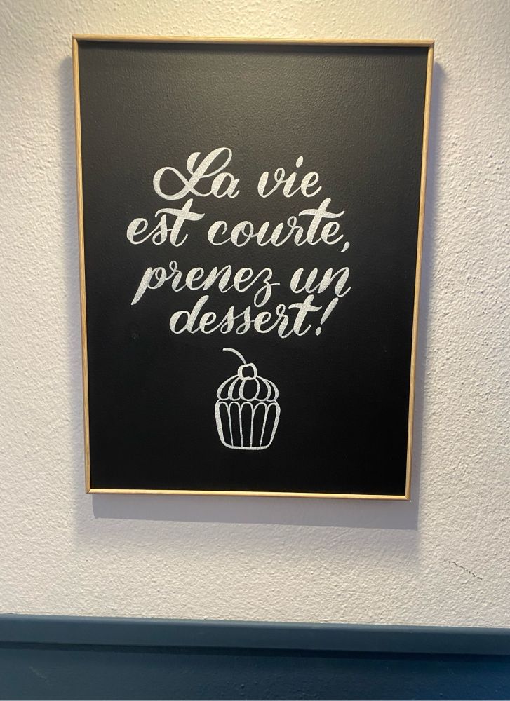 Pancarte affichée au mur avec la phrase: “la vie est courte, prenez un dessert !”