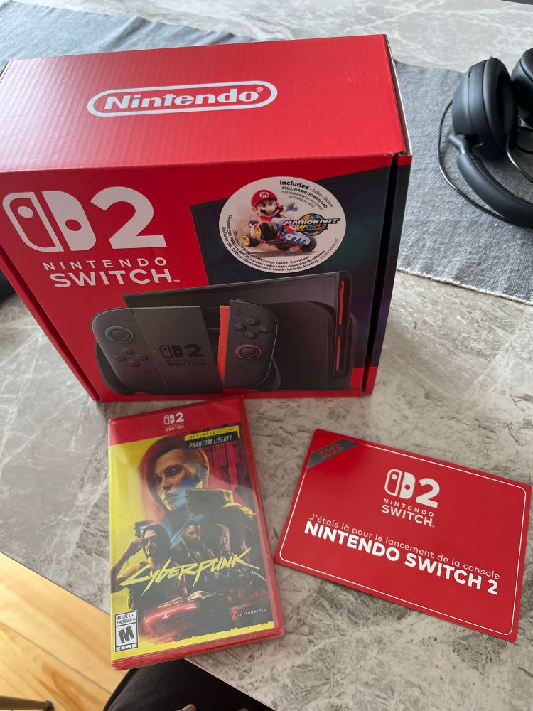 A Switch 2 Mario Kart Bundle still in the box on a table with a copy of Cyberpunk 2077 and a proof certificat of being present at the Switch 2 launch.