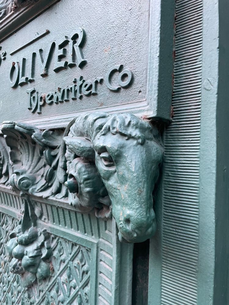 photograph of a ram’s head supporting a plaque with the text The Oliver Typewriter Co