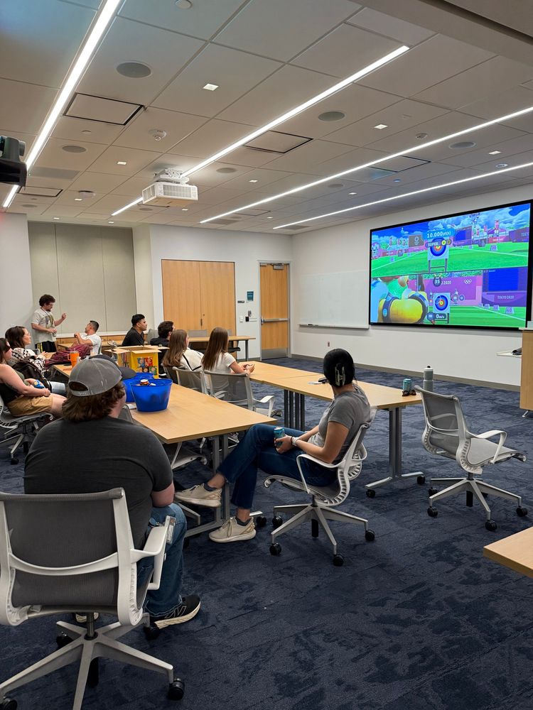 Nintendo Switch Sonic Olympics game up on a projector screen with 10 people watching and 

